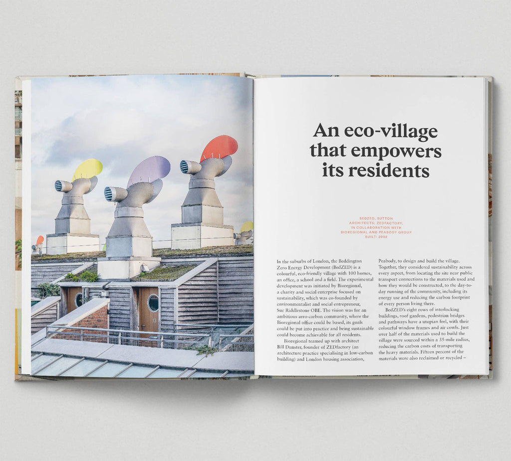 Open book showing architectural design with colorful sculptures and text about an eco-village.