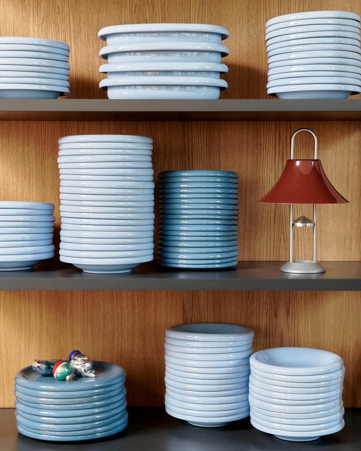 Stacks of ceramic bowls on shelves with a red lamp in the background.
