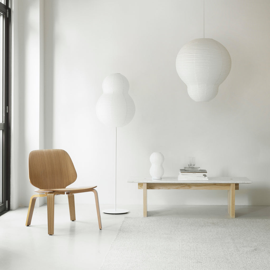 Modern interior with a wooden chair, table, and pendant lights against a white wall.