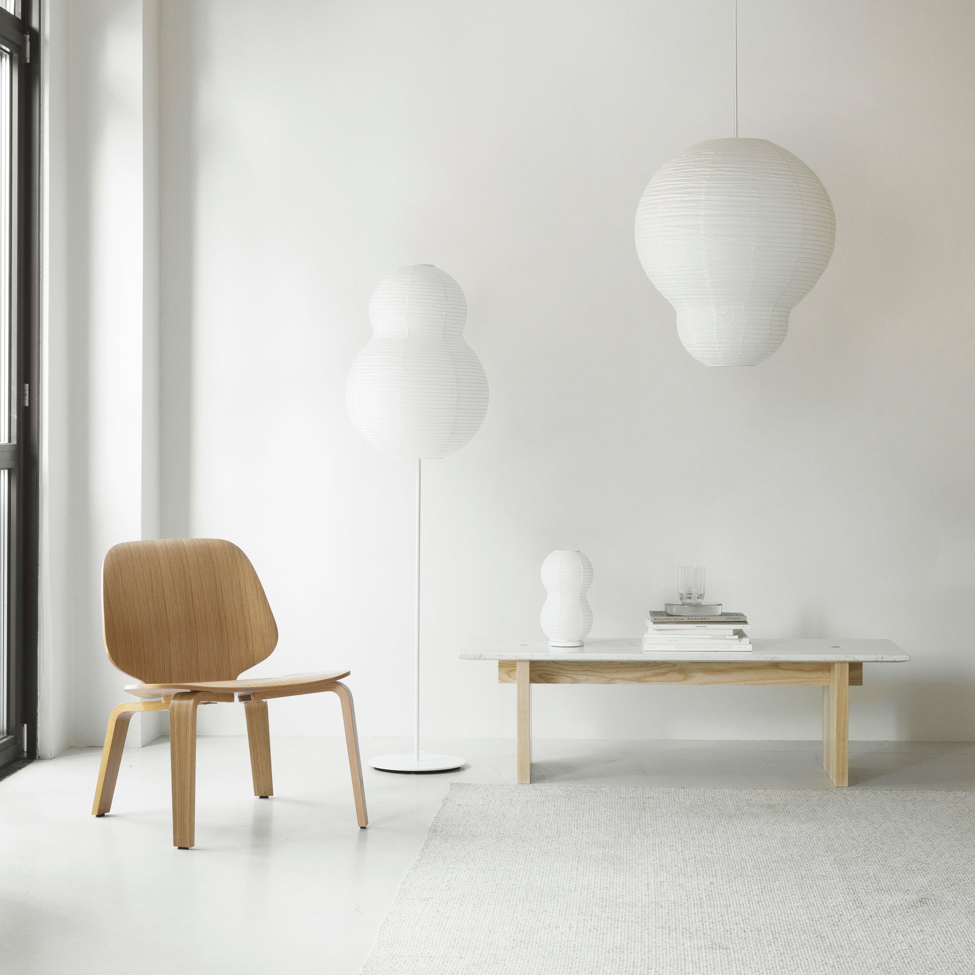 Modern interior with a wooden chair, table, and pendant lights against a white wall.