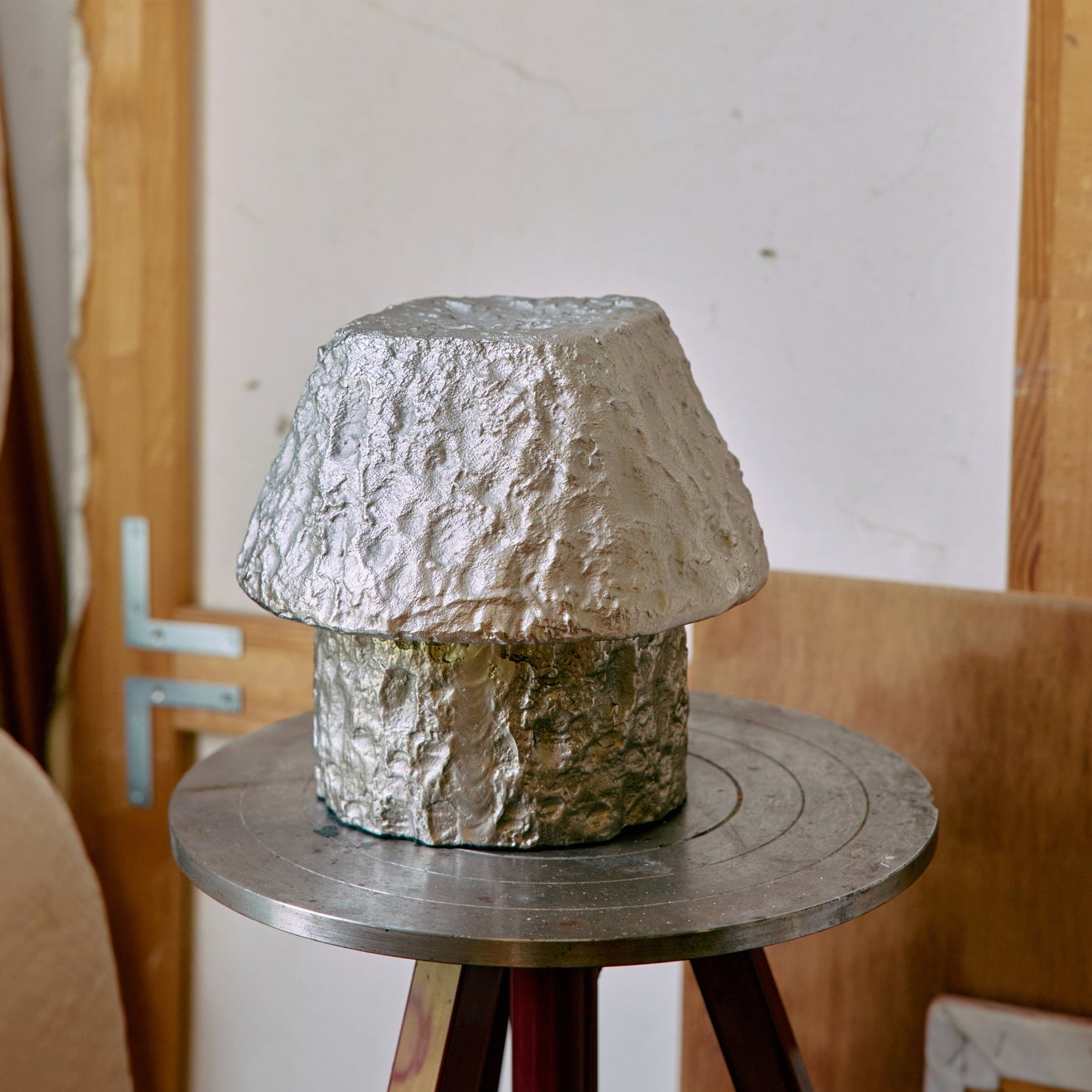 Textured stone-like lamp on a wooden stool against a plain wall.