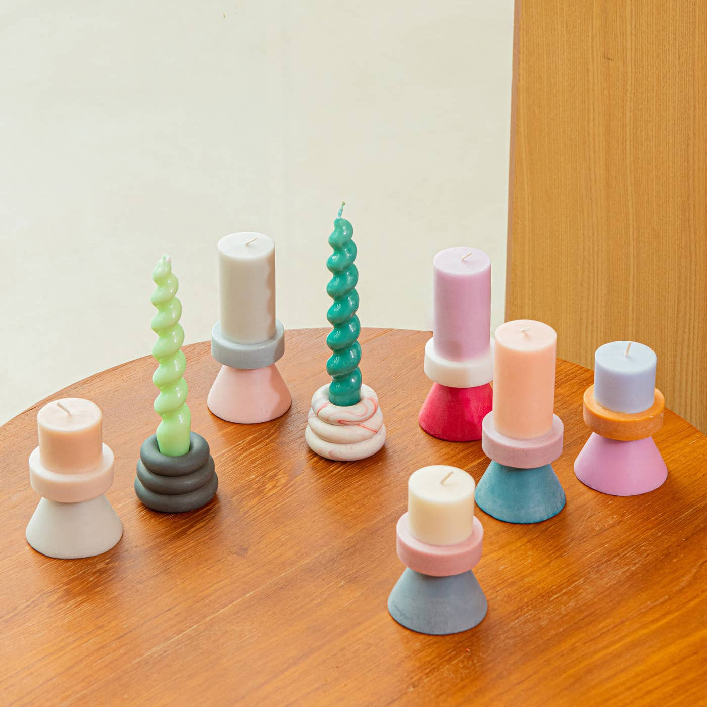 Colorful candles in various holders on a wooden surface