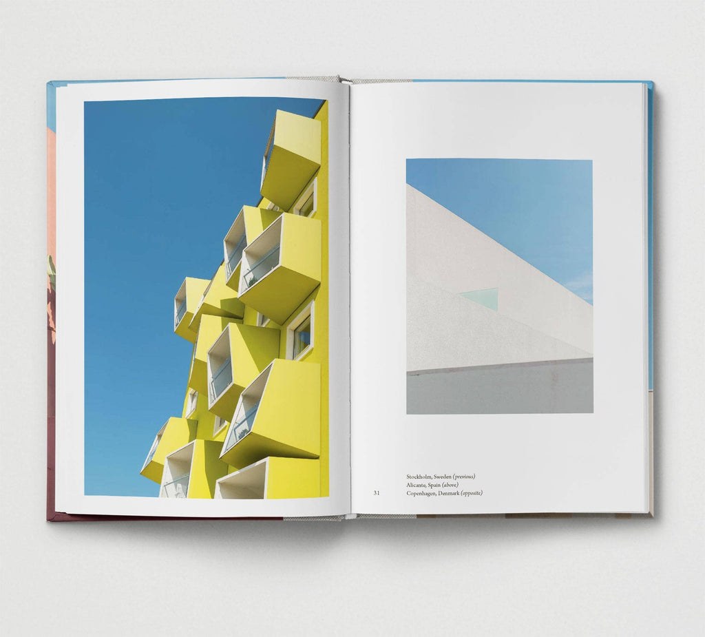 Open book showing images of modern architecture with a yellow building and blue sky on one page, and a white building on the other.