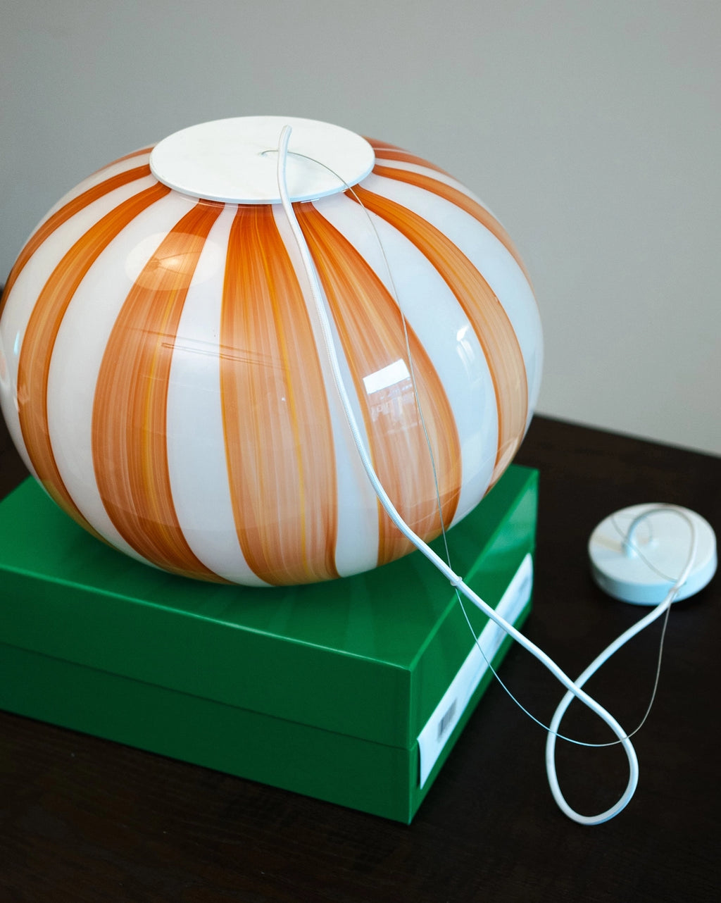 Decorative lamp with orange and white stripes on a green base