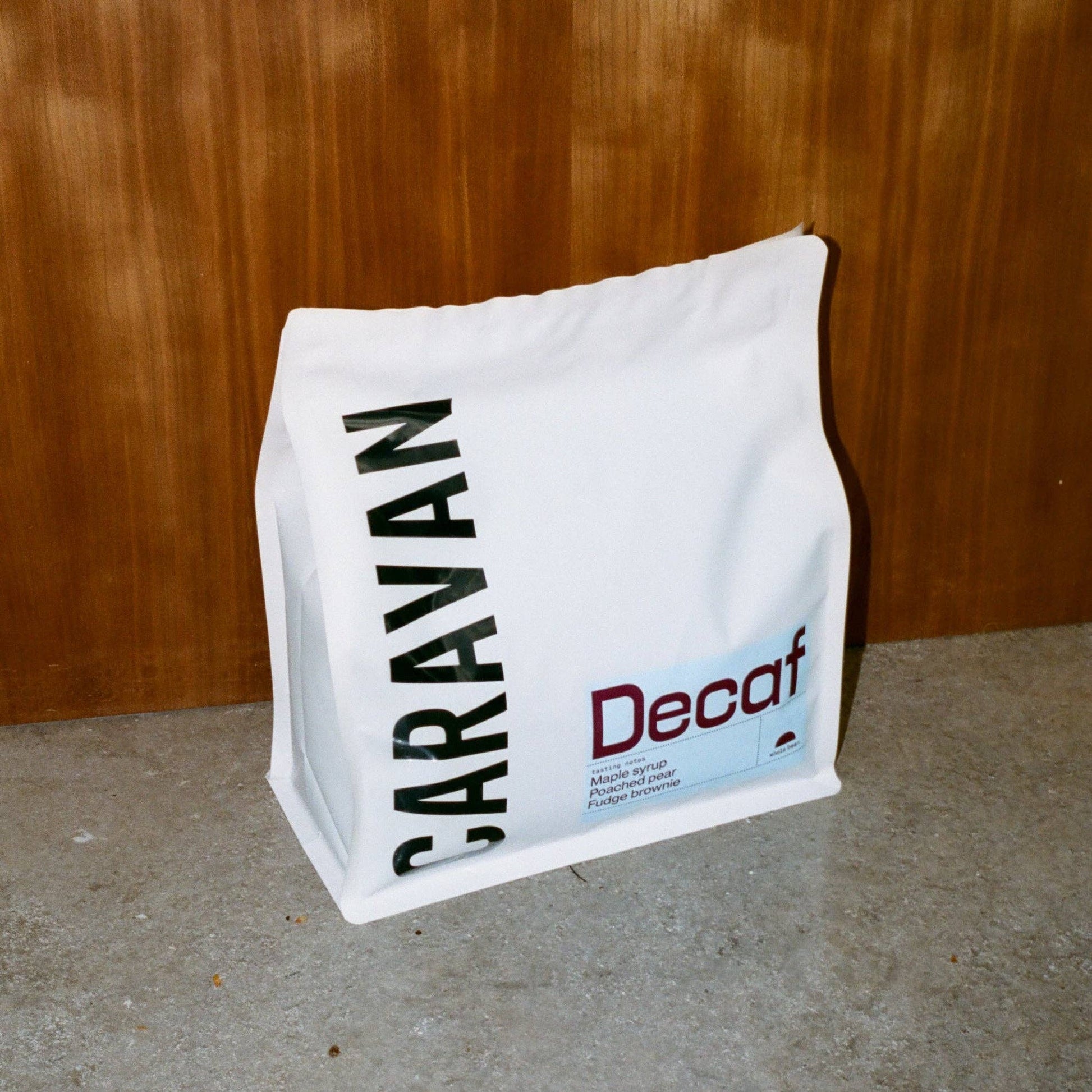 White bag with 'BARAVAN' and 'Decaf' text against a wooden background
