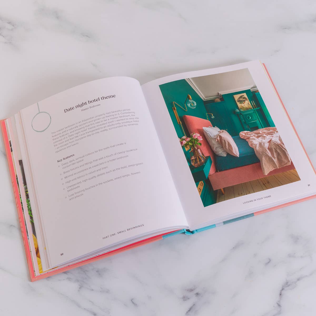 Open book showing a page with text and a colorful interior design image on a marble surface
