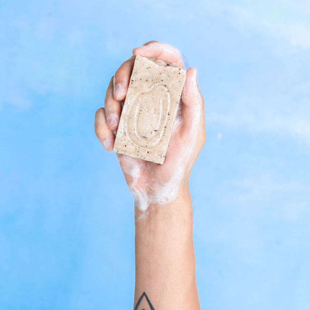 Hand holding foaming soap in sky