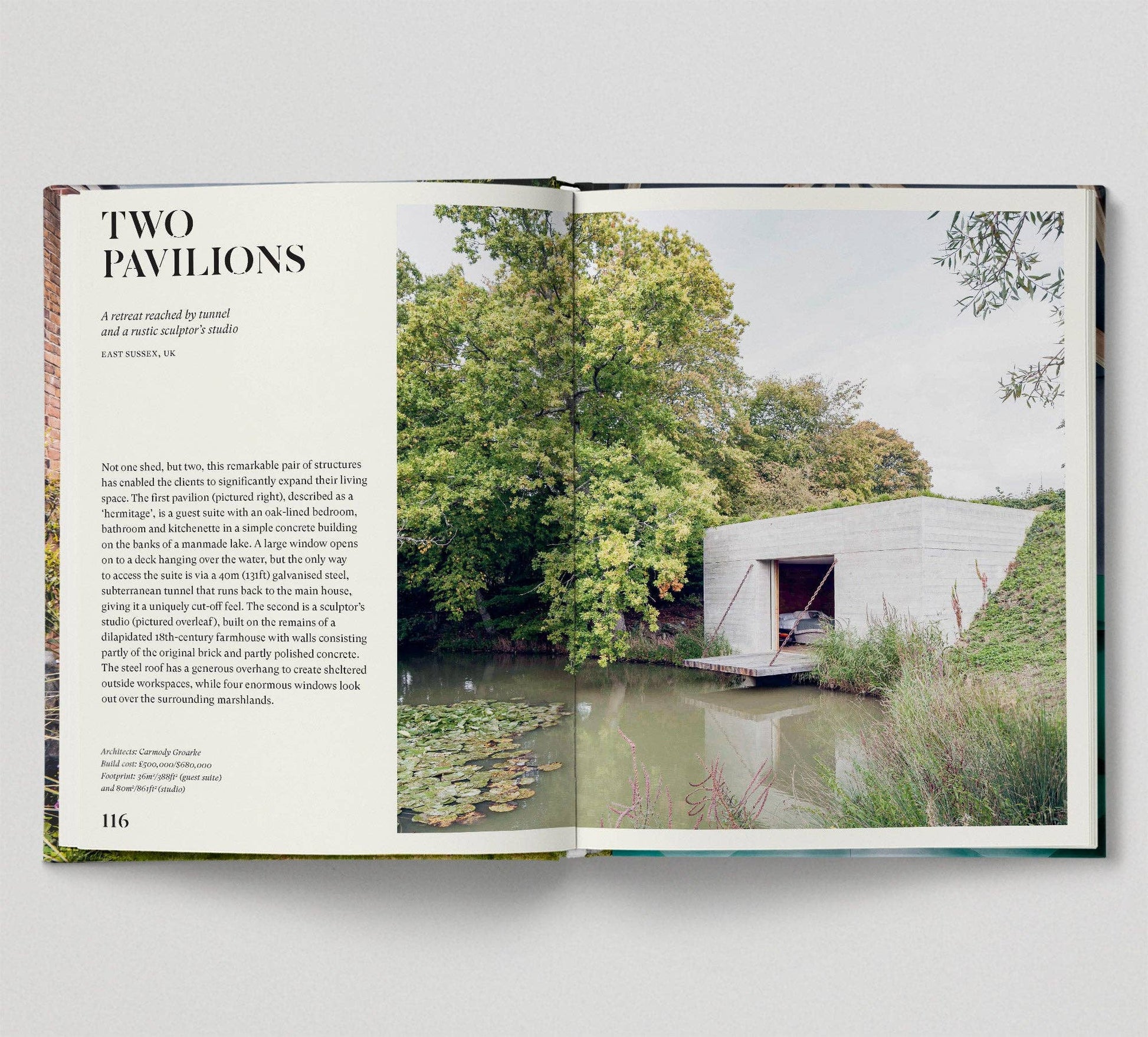 Open book showing a photograph of a modern building by a pond with trees in the background.