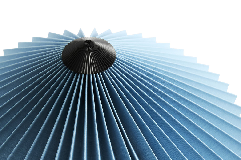 Blue pleated lampshade with a black base on a white background