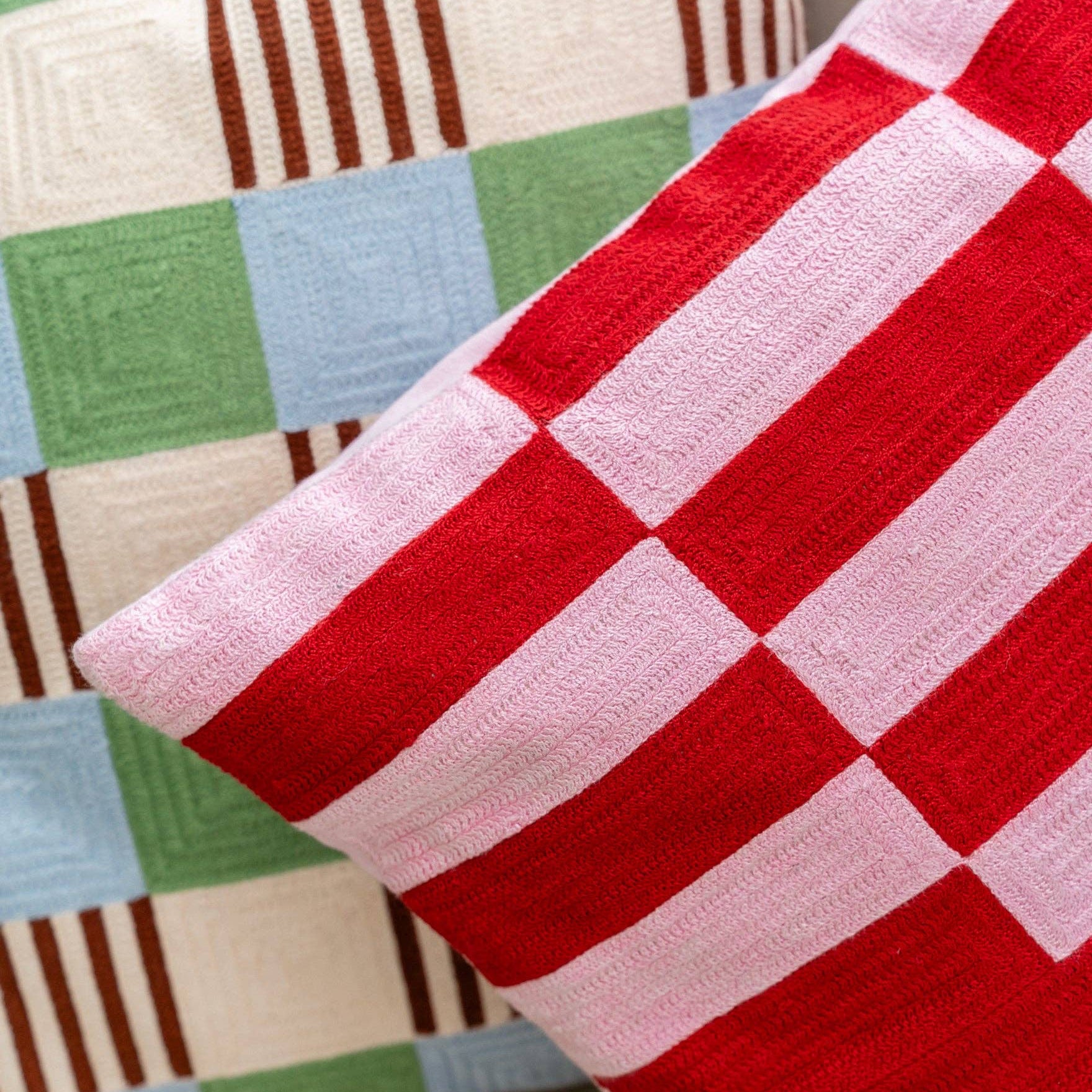 Close-up of a red and pink checkered fabric with a multicolored patchwork background.