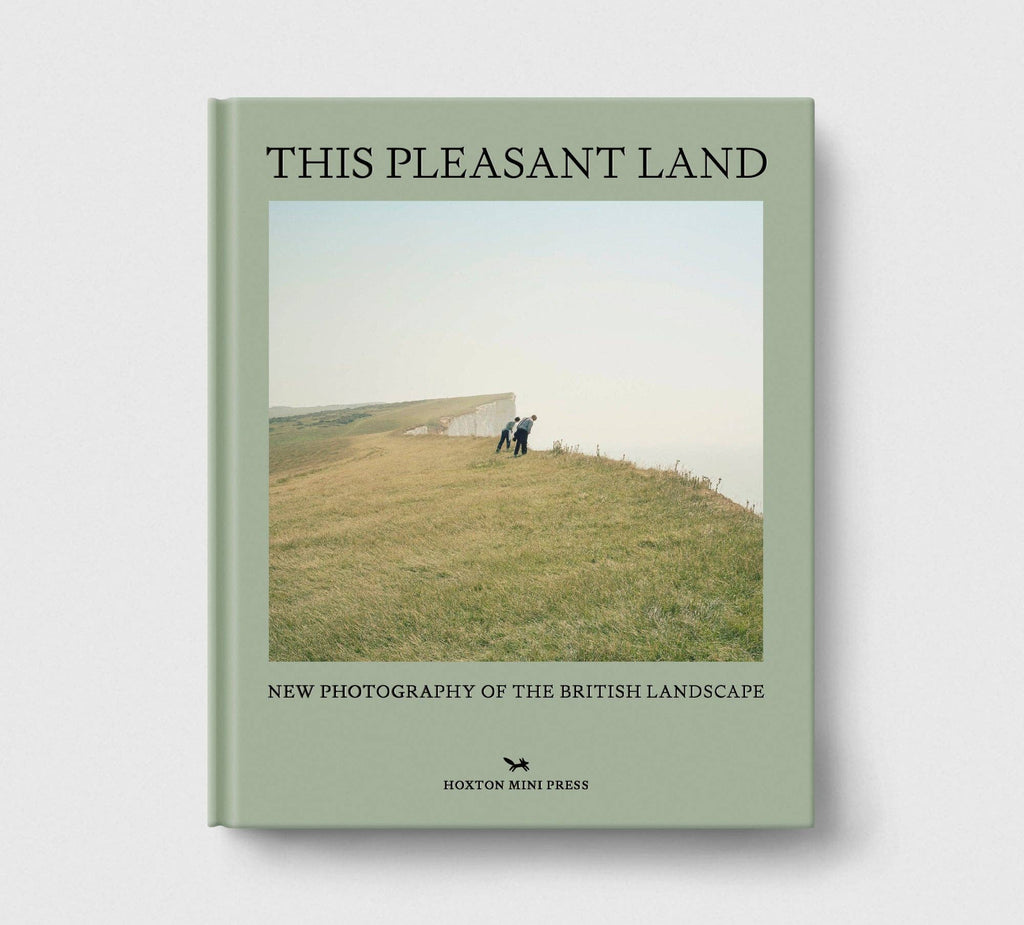 Book titled 'This Pleasant Land' with a cover photo of two people on a hillside.