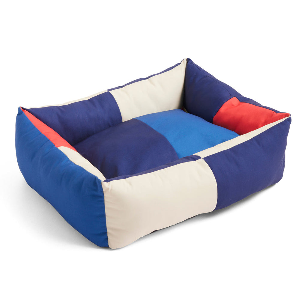 Color-blocked pet bed with blue, red, and beige sections on a white background