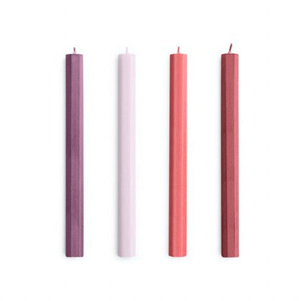 Four candles of different colors arranged in a row on a white background