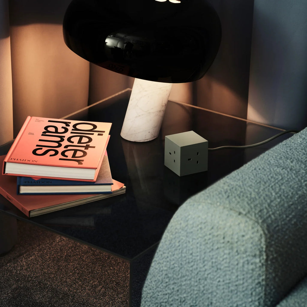 Nightstand with books and a lamp next to a sofa