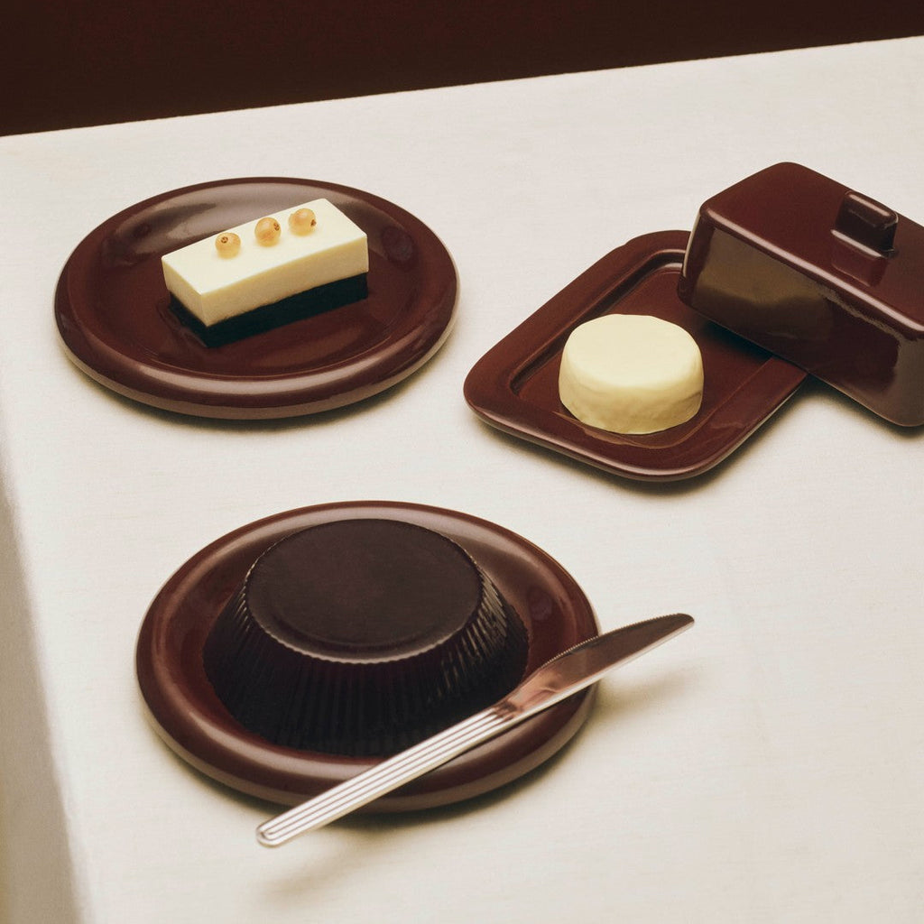 Dessert plating with a small cake, a scoop of ice cream, and a chocolate dessert on a white surface.
