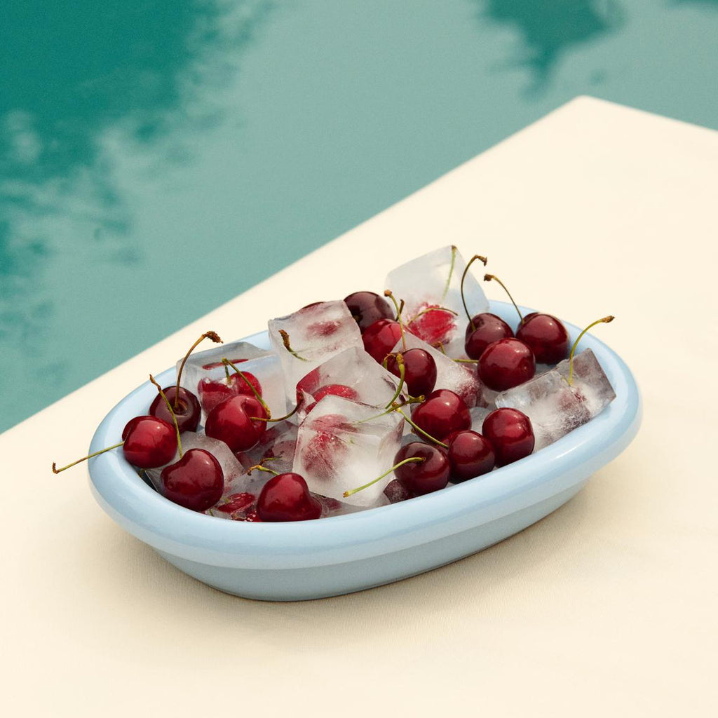 Bowl of cherries and ice cubes by a pool