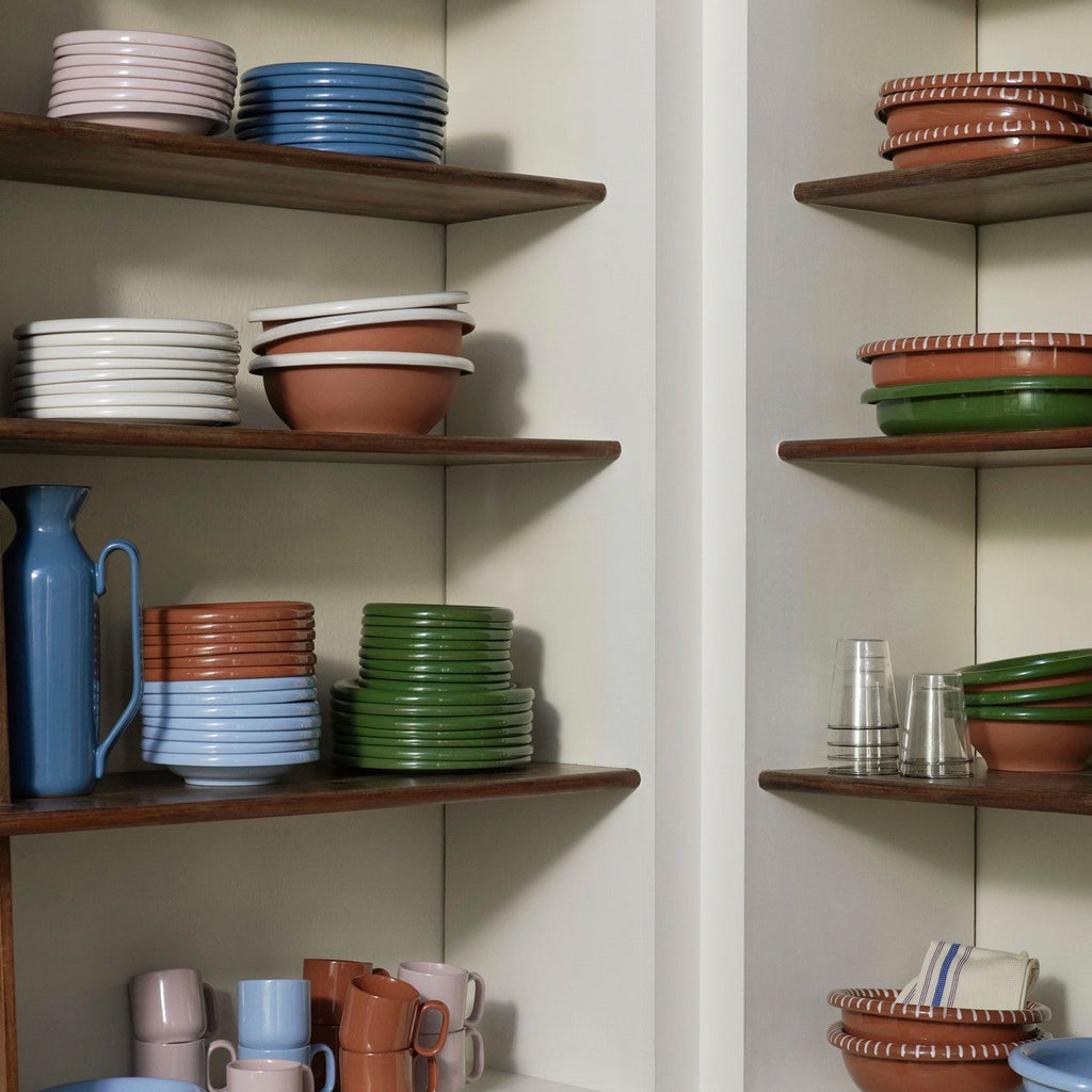 Corner of a kitchen with wooden shelves displaying various ceramic dishes and cookware.