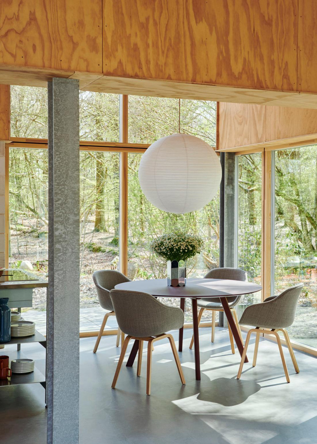 Modern dining area with a round table and chairs in a room with large windows.