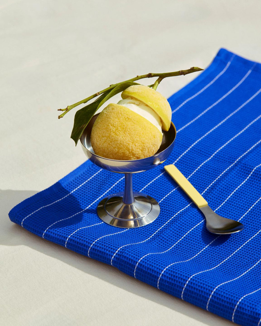 Dessert with a yellow sponge cake and lemon on a blue striped towel with a spoon
