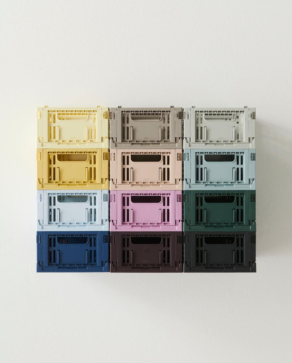Coloured storage crates stacked on top of each other in square formation on white background
