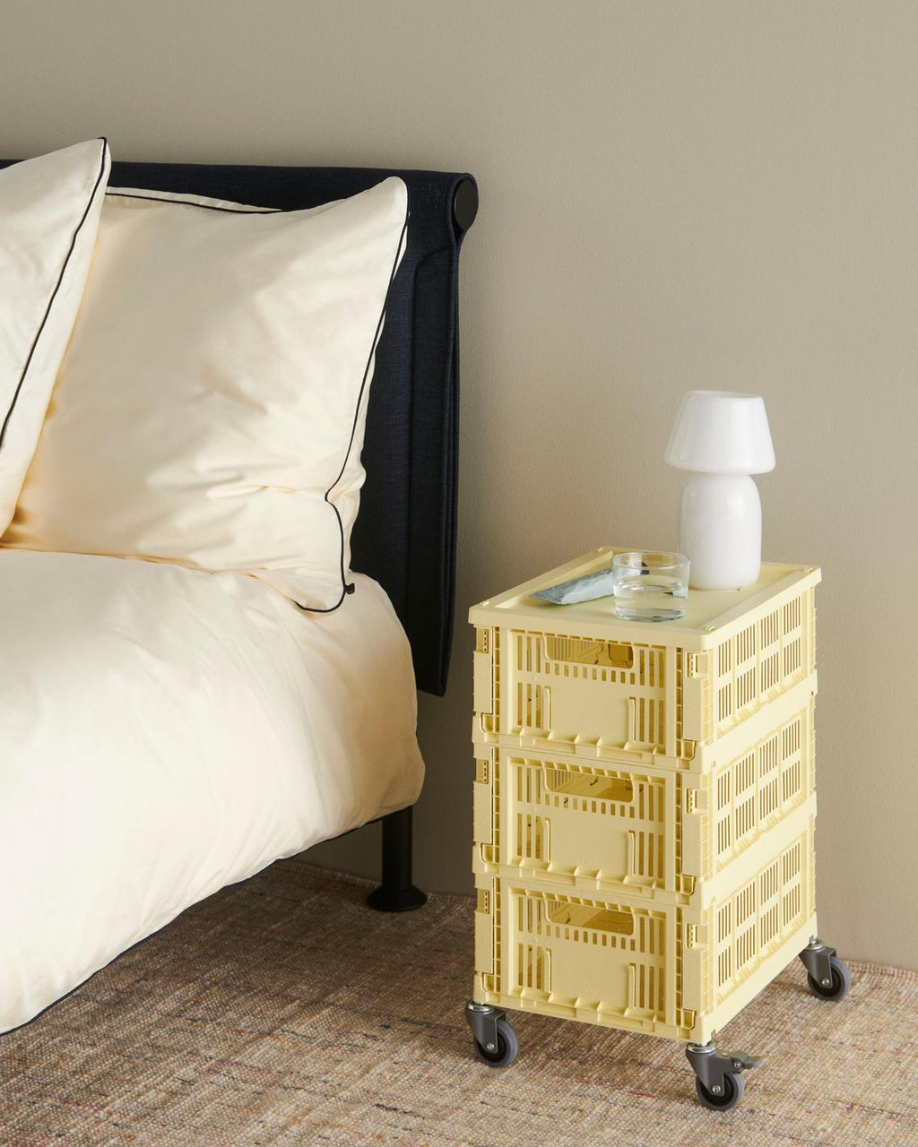 Yellow crate nightstand next to a bed with a lamp on top