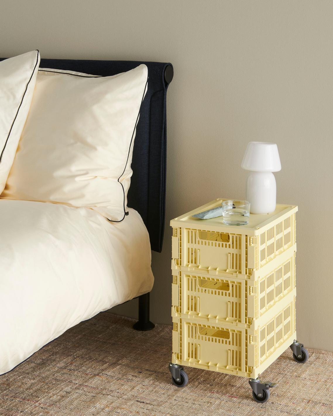 Yellow crate nightstand next to a bed with a lamp on top
