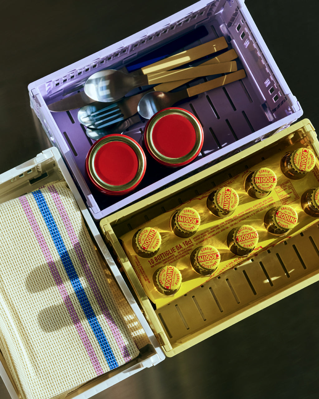 Purple and yellow storage crates holding cutlery and tea towels in restaurant setting