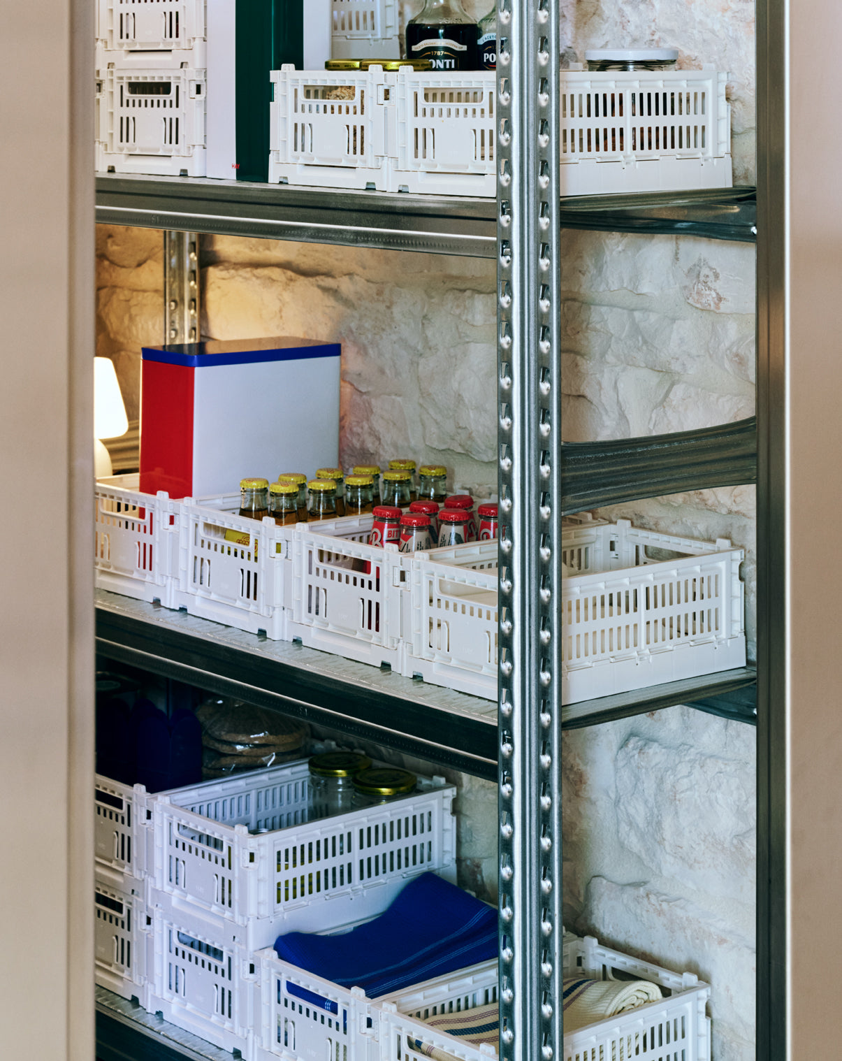 Shelving unit with white storage crates and containers on a stone wall background