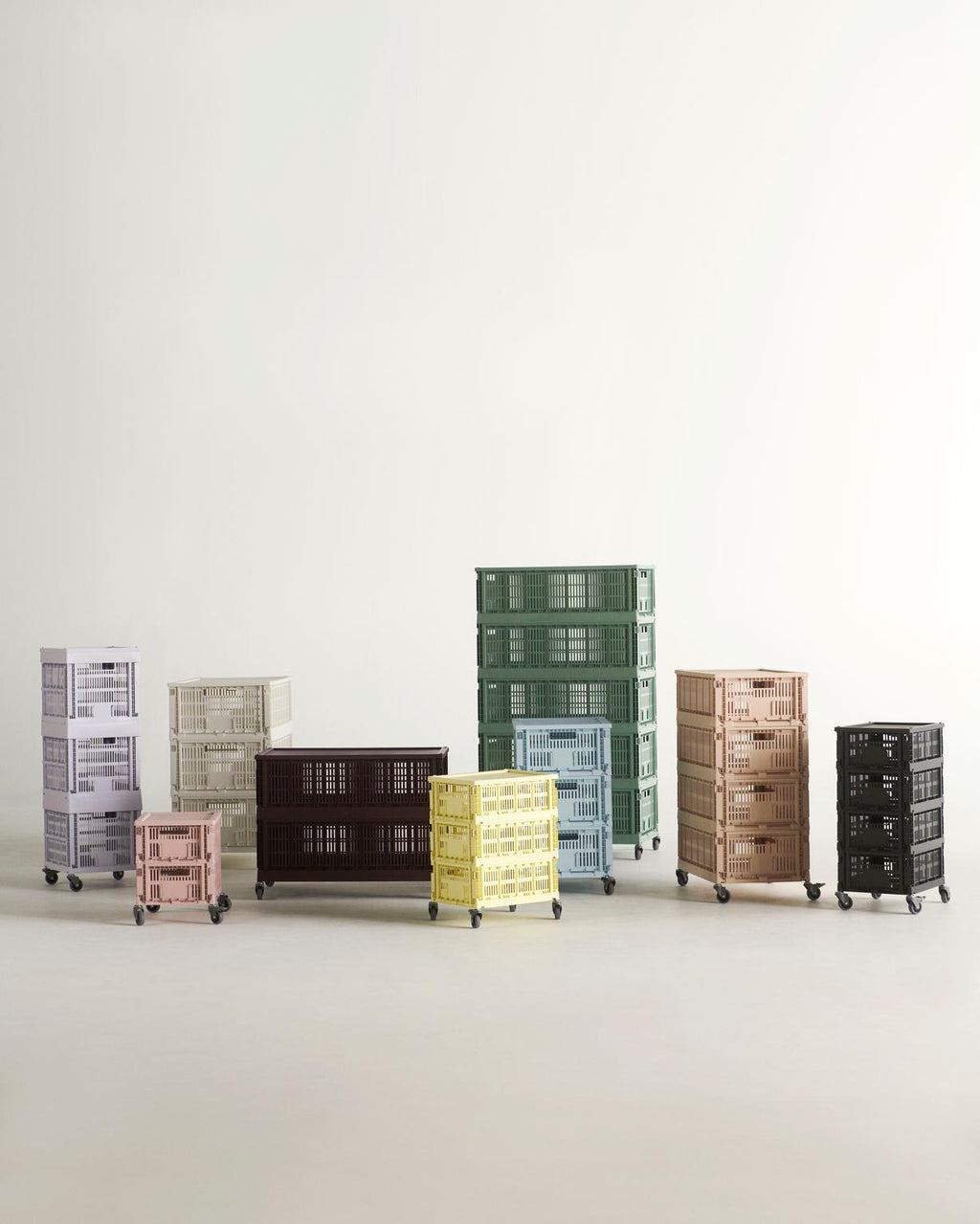 Collection of colorful storage crates on wheels against a white background