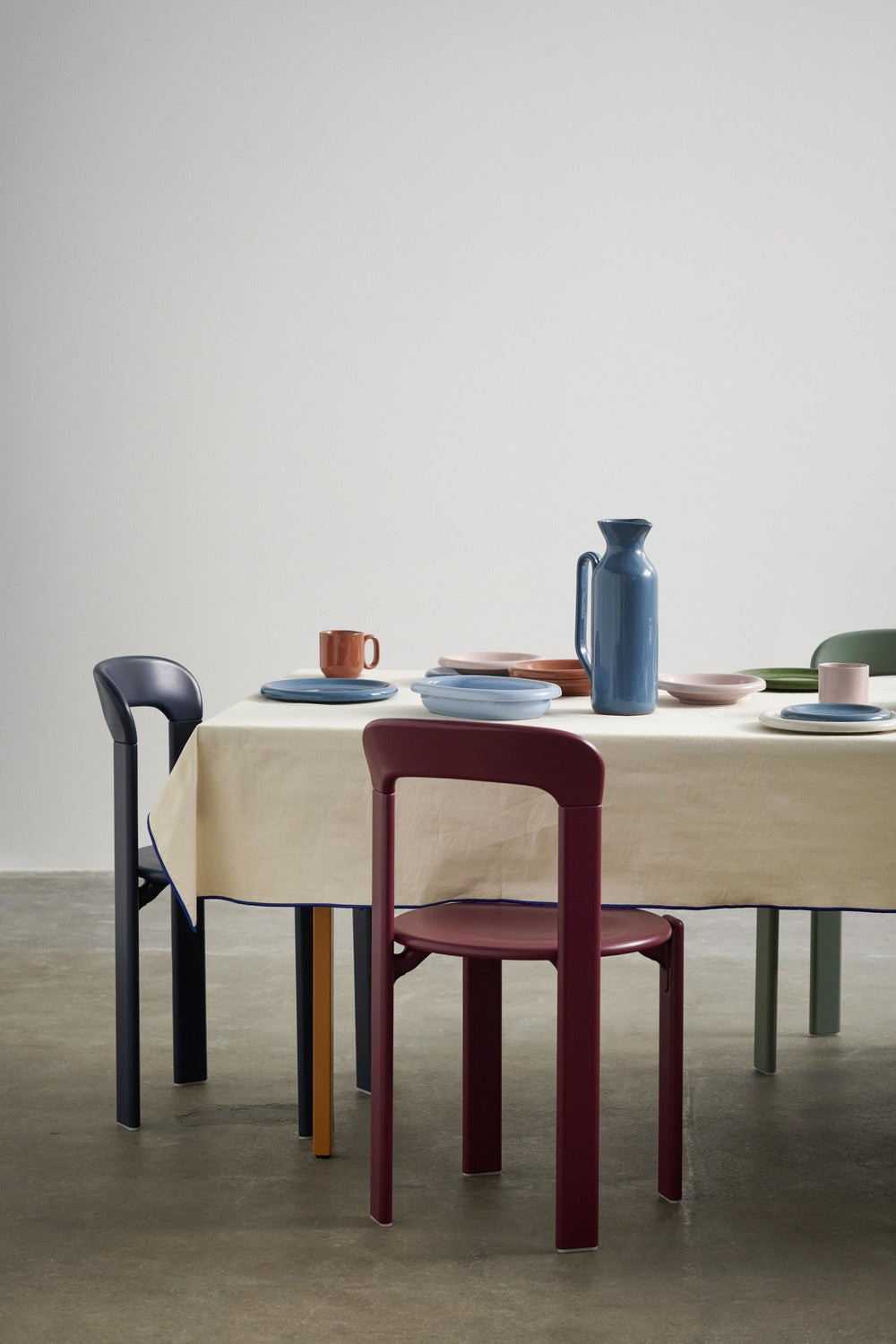 Dining table with chairs and tableware against a plain wall