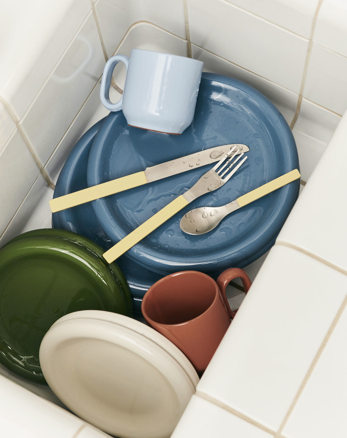 Colorful ceramic dishes and cutlery on a tiled floor