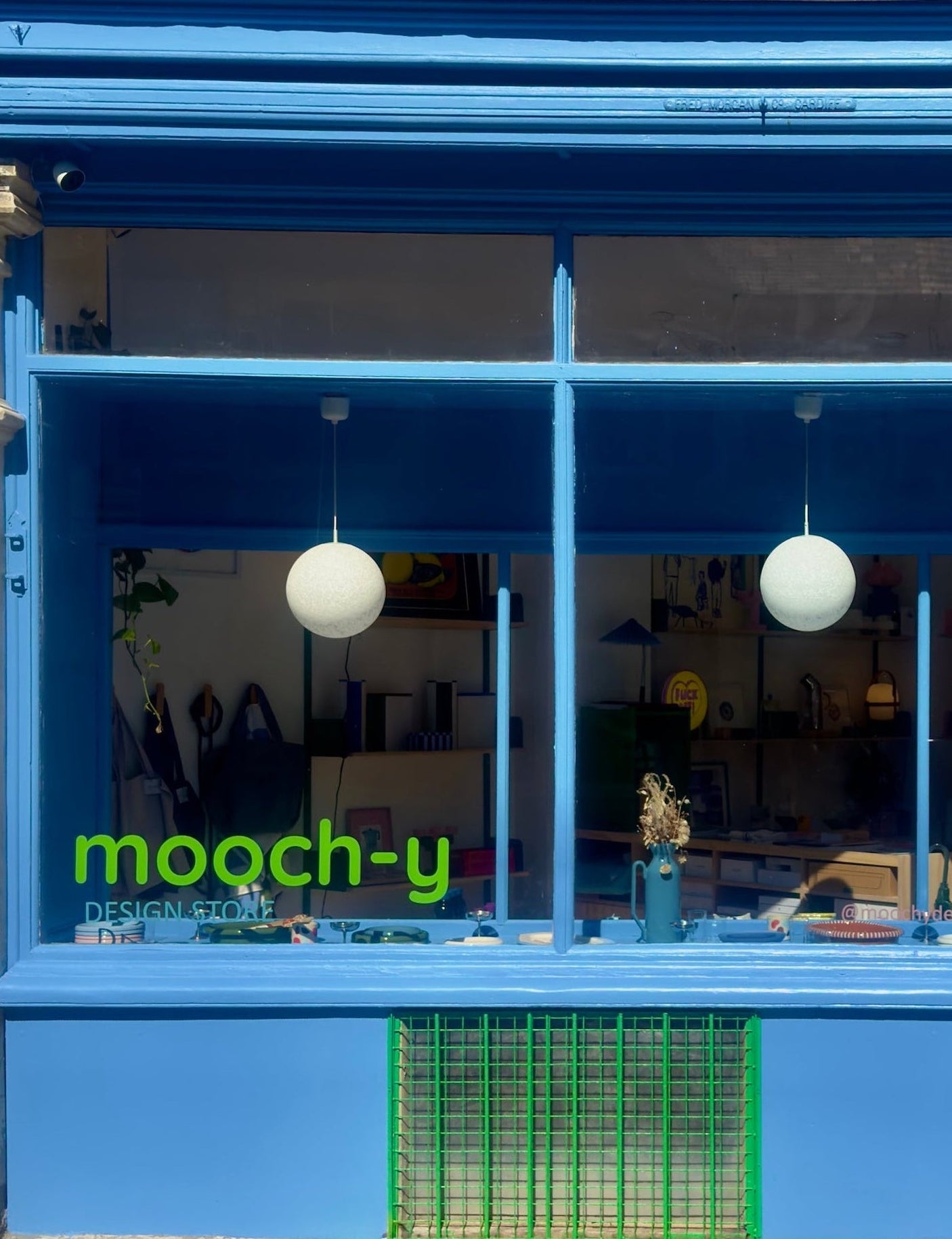 Blue storefront with 'mooch-y' sign on a stone building
