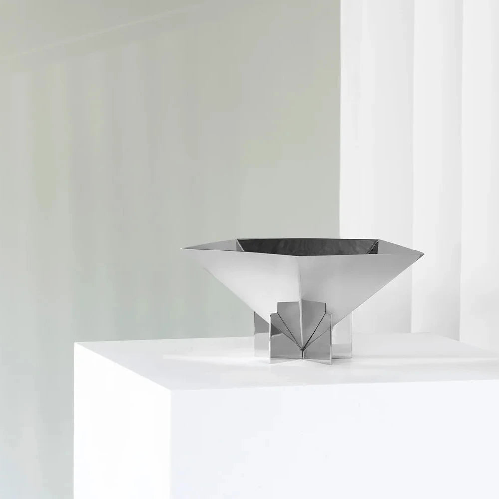 Modern silver bowl on a white surface with a light gray background