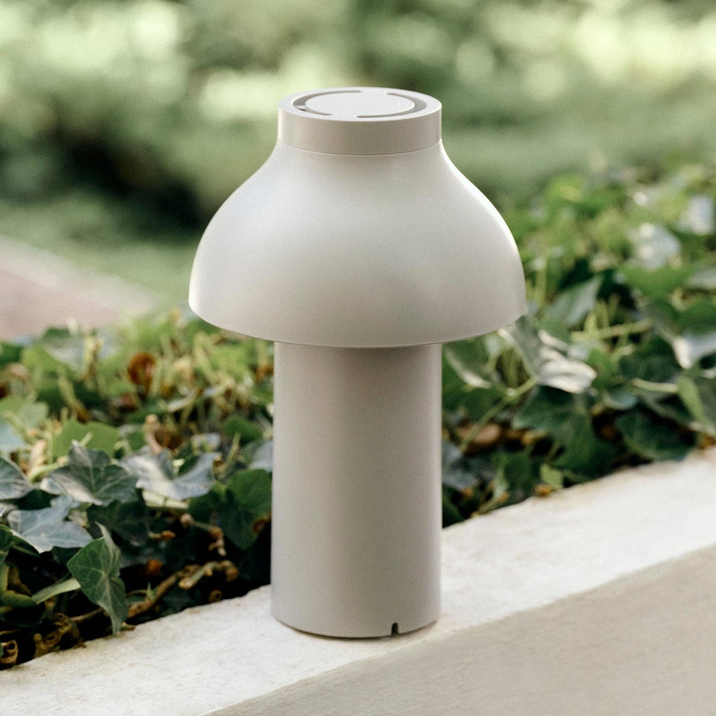 White outdoor lamp on a concrete surface with greenery in the background