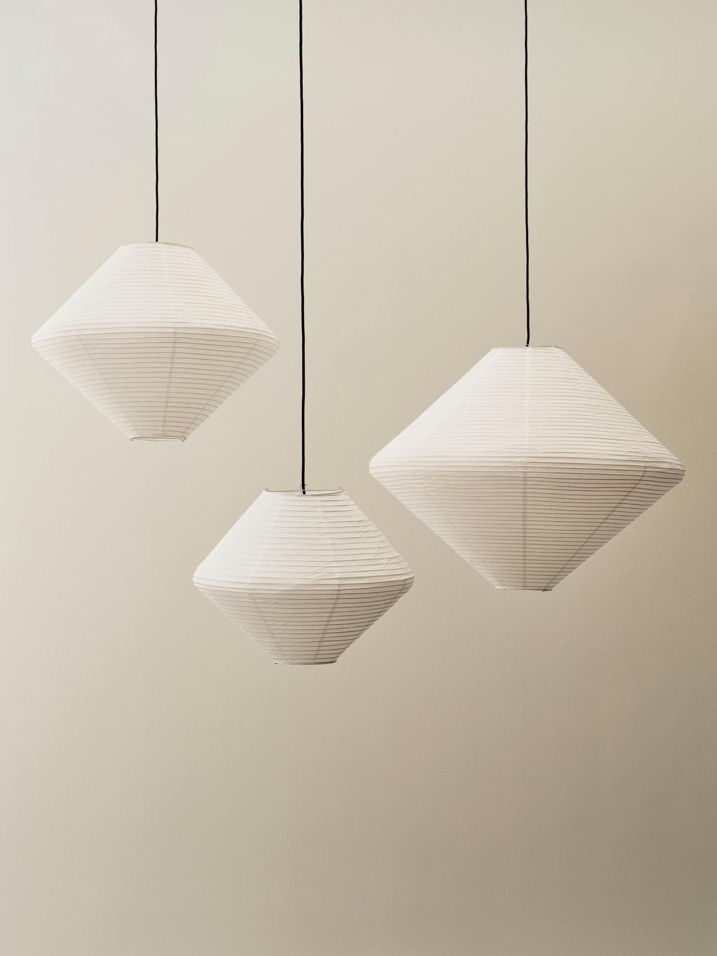 Three geometric pendant lights hanging against a plain wall.