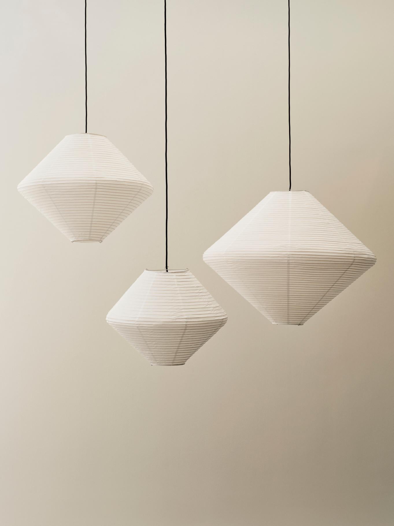 Three geometric pendant lights hanging against a plain wall.