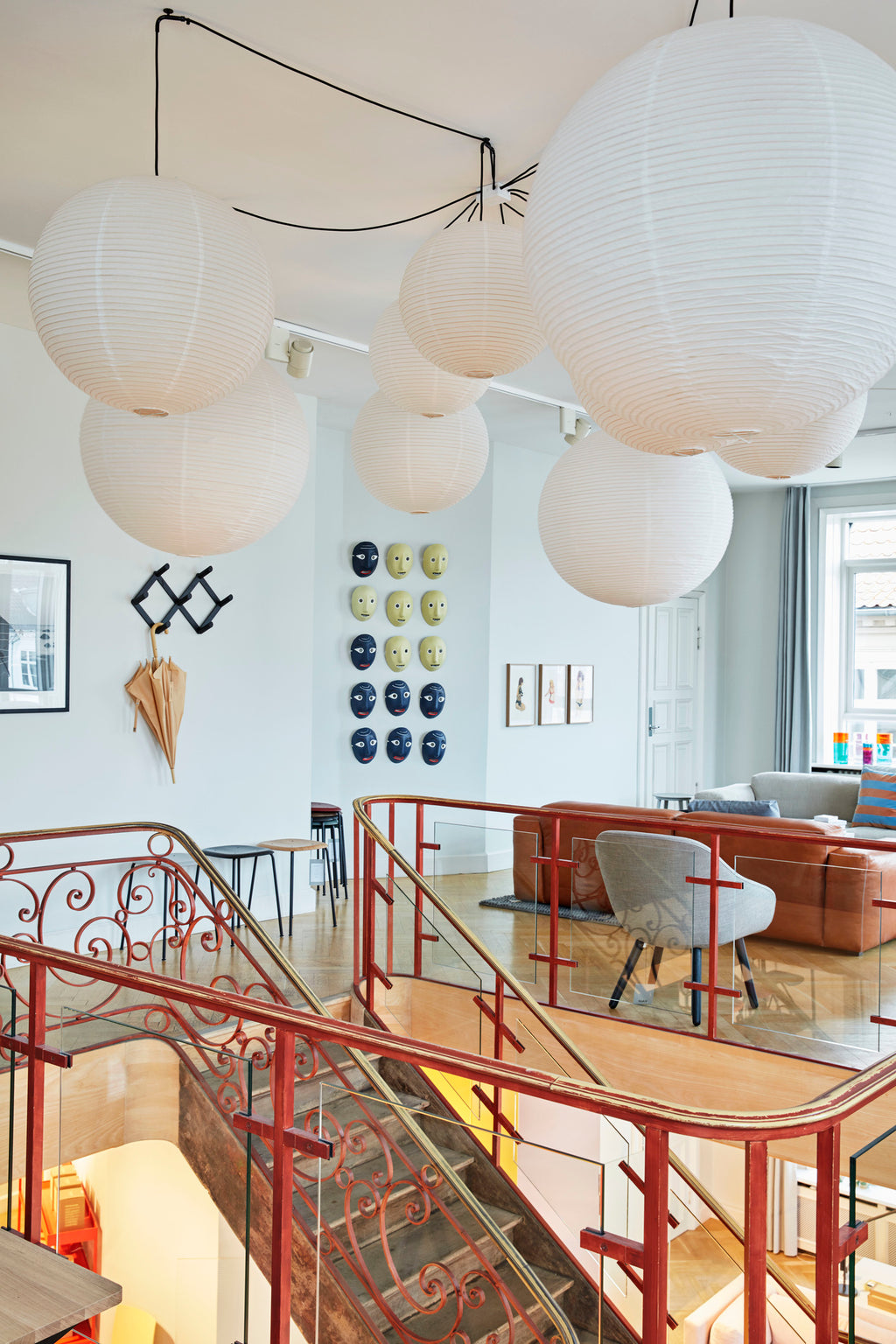 Modern interior with paper lamp shades, red staircase, and decorative wall hangings