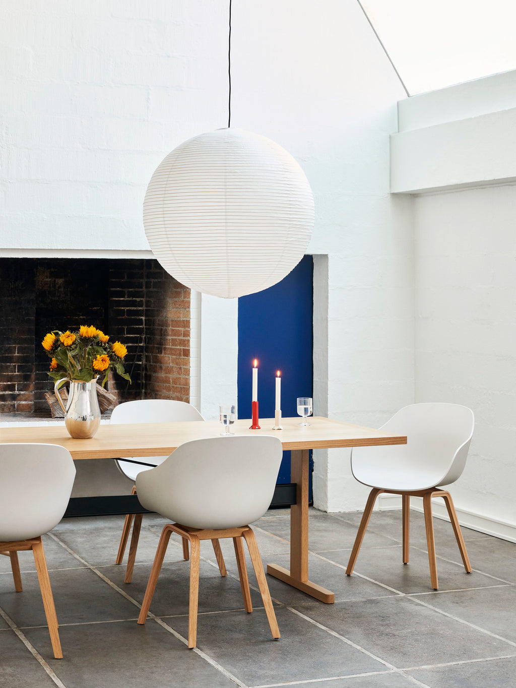 Large paper lampshade hanging in modern dining room setting with candles and sunflowers