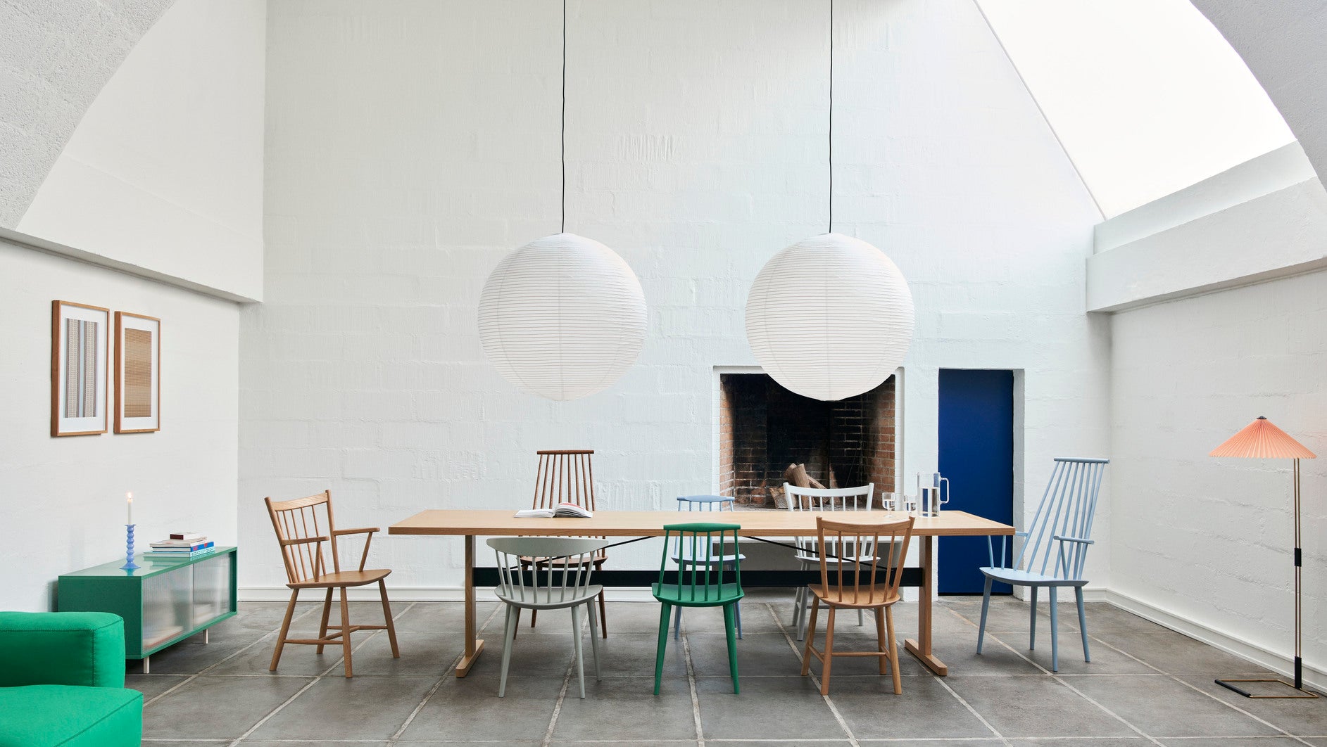 Modern dining area with a long wooden table and various chairs in a minimalistic setting.