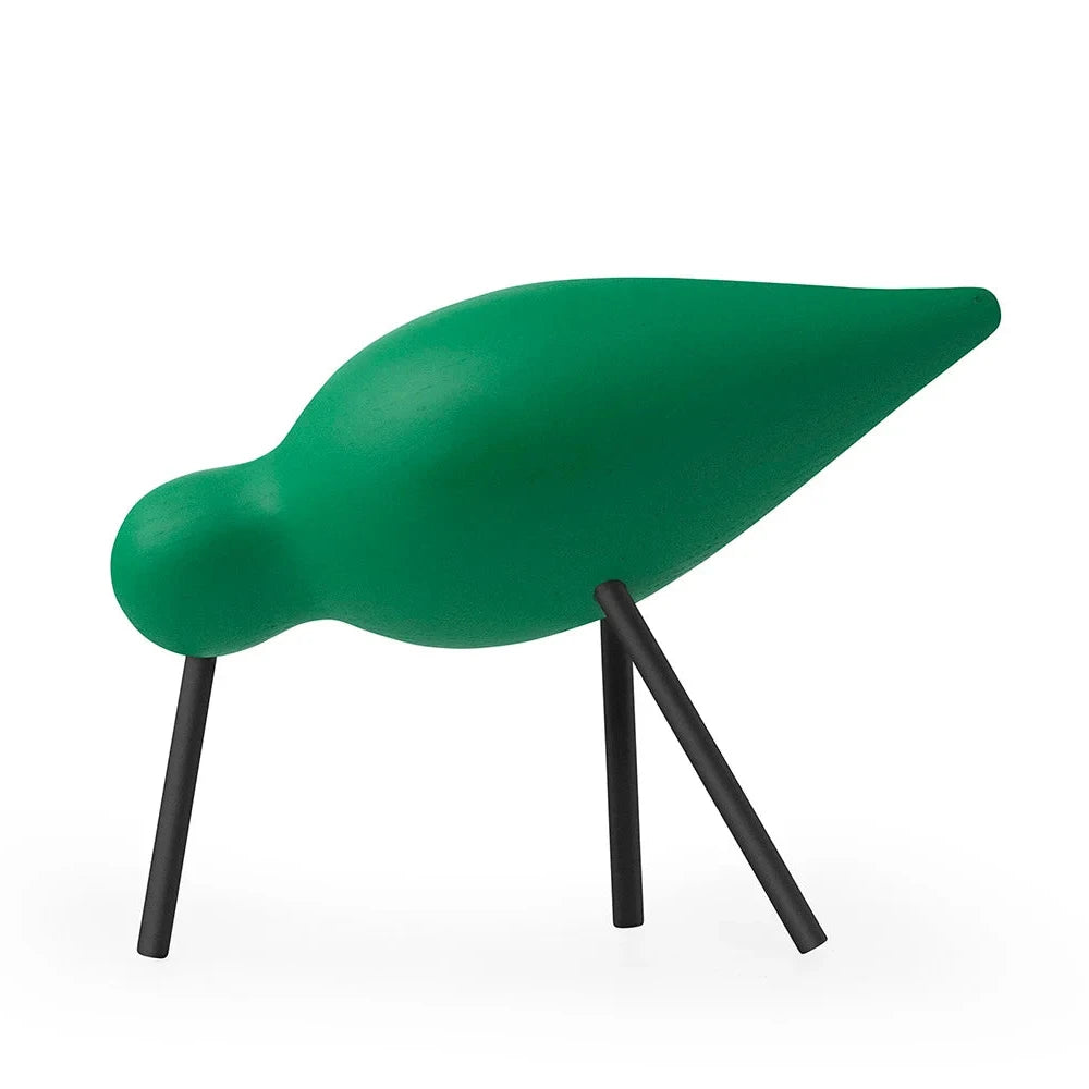 Green bird-shaped object with black legs on a white background