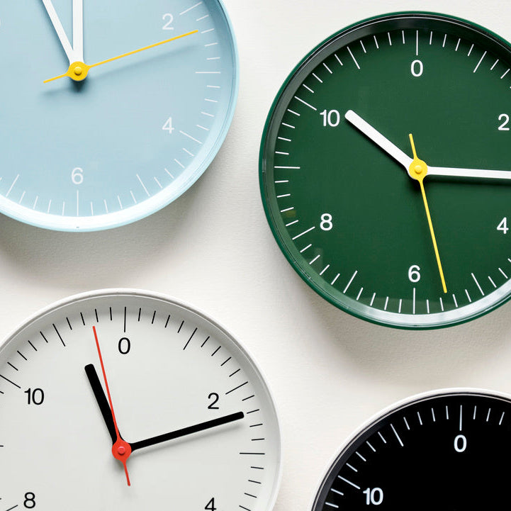 Multicoloured wall clocks on white background