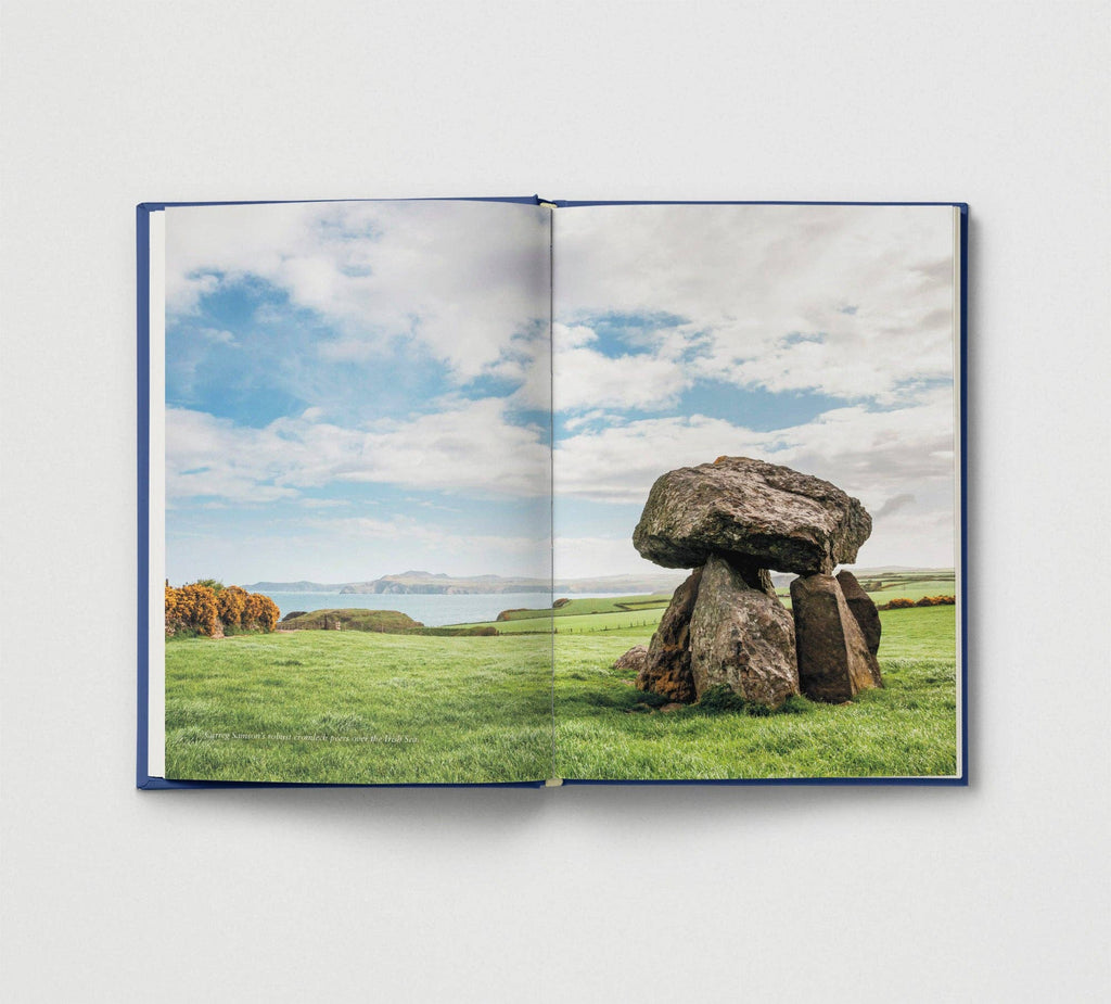 Open book showing a stone monument in a field with a blue sky.