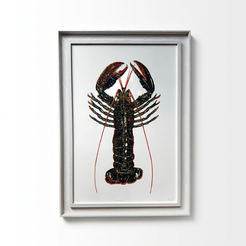 Framed lobster art print featuring a detailed lobster illustration in black, red, and green on a white background, housed in a light gray frame and mounted on a white wall.