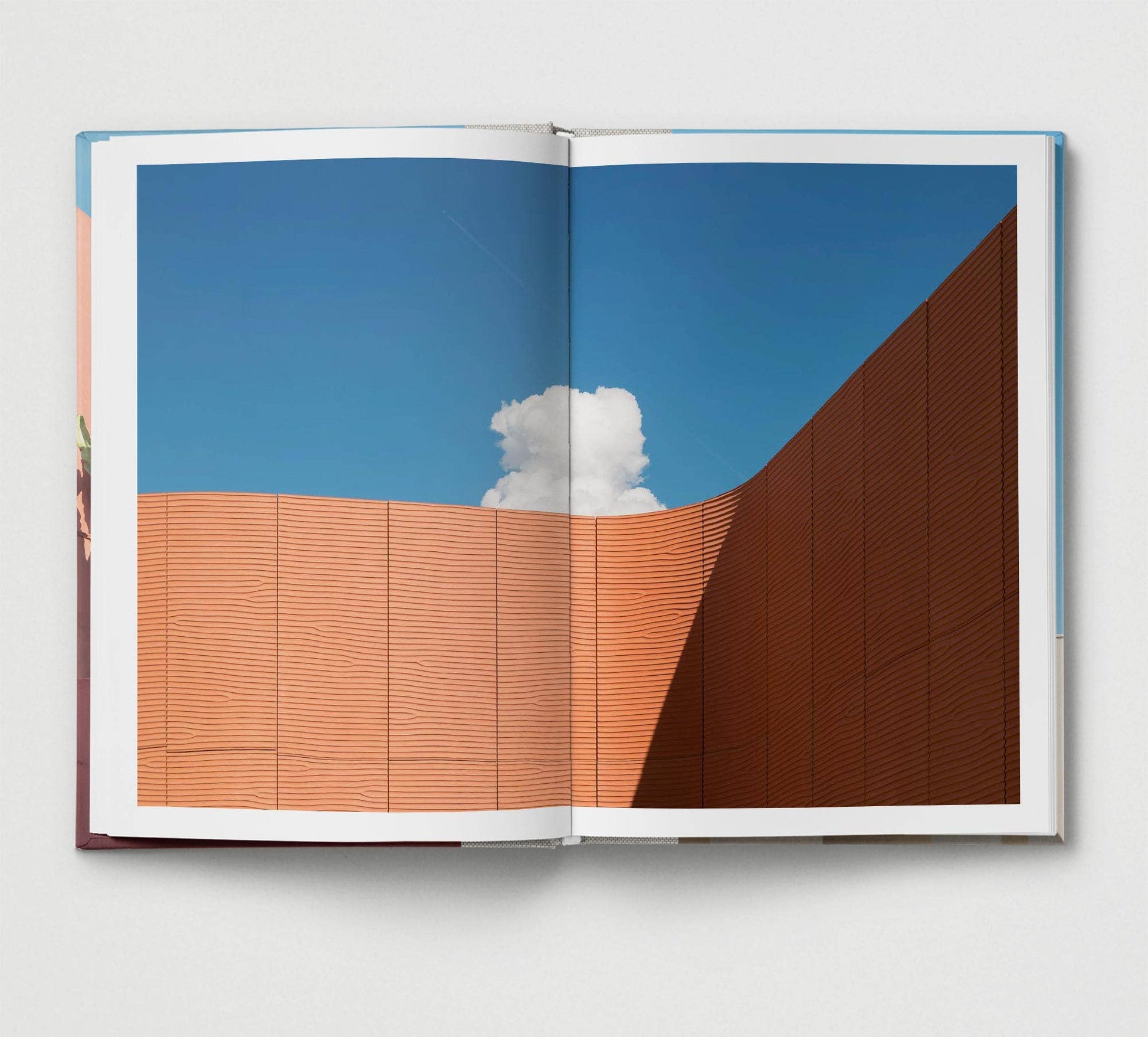 Open book showing a photograph of a building with a blue sky and cloud.