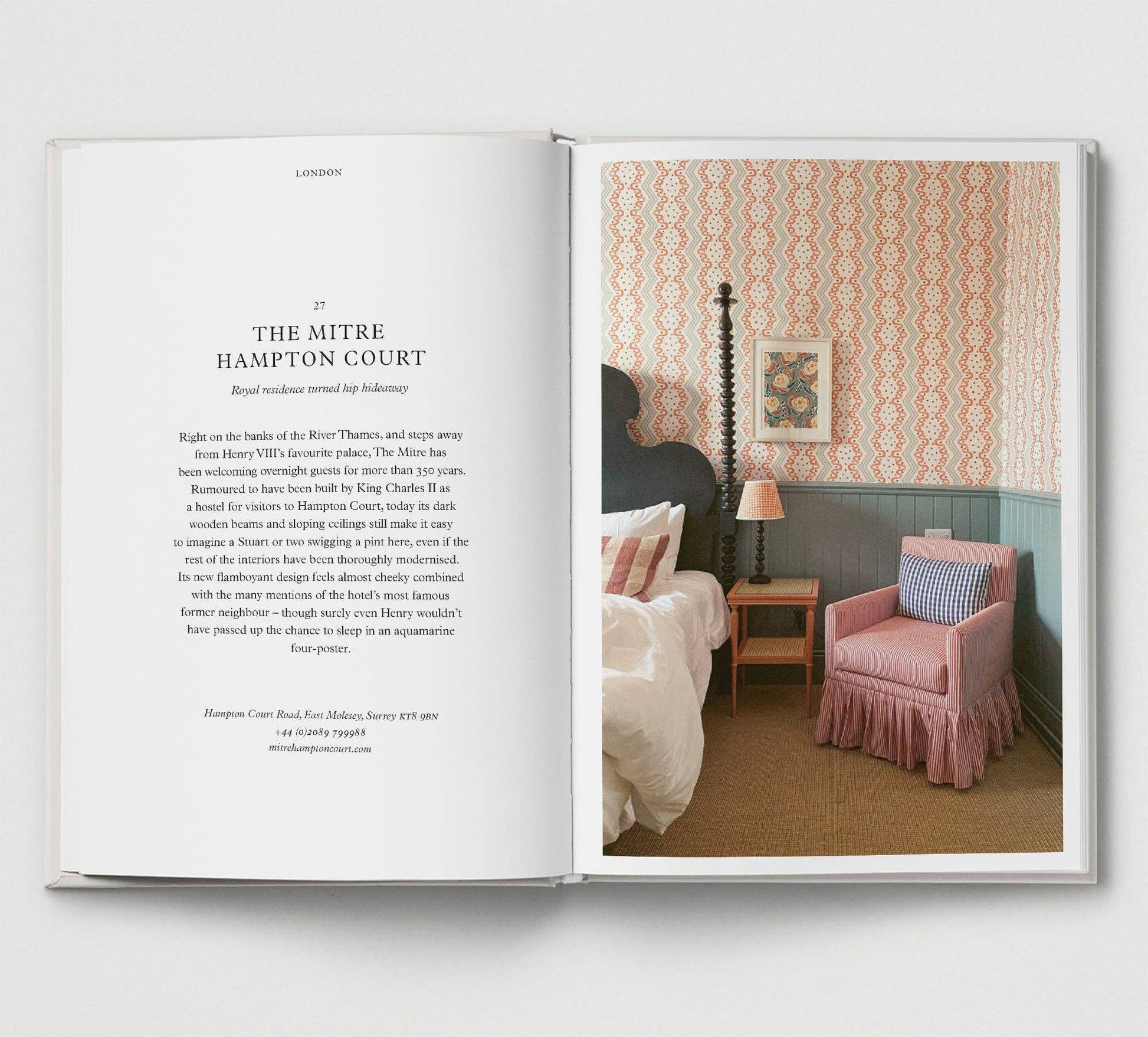 Open book showing a bedroom interior with patterned wallpaper and pink armchair.
