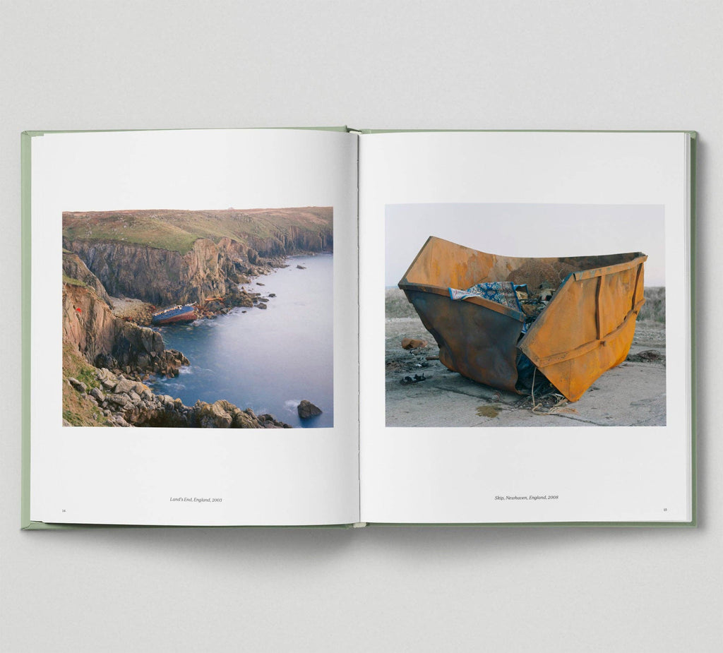 Open book showing two photographs: one of a coastal scene with cliffs and water, and another of a rusted metal container.