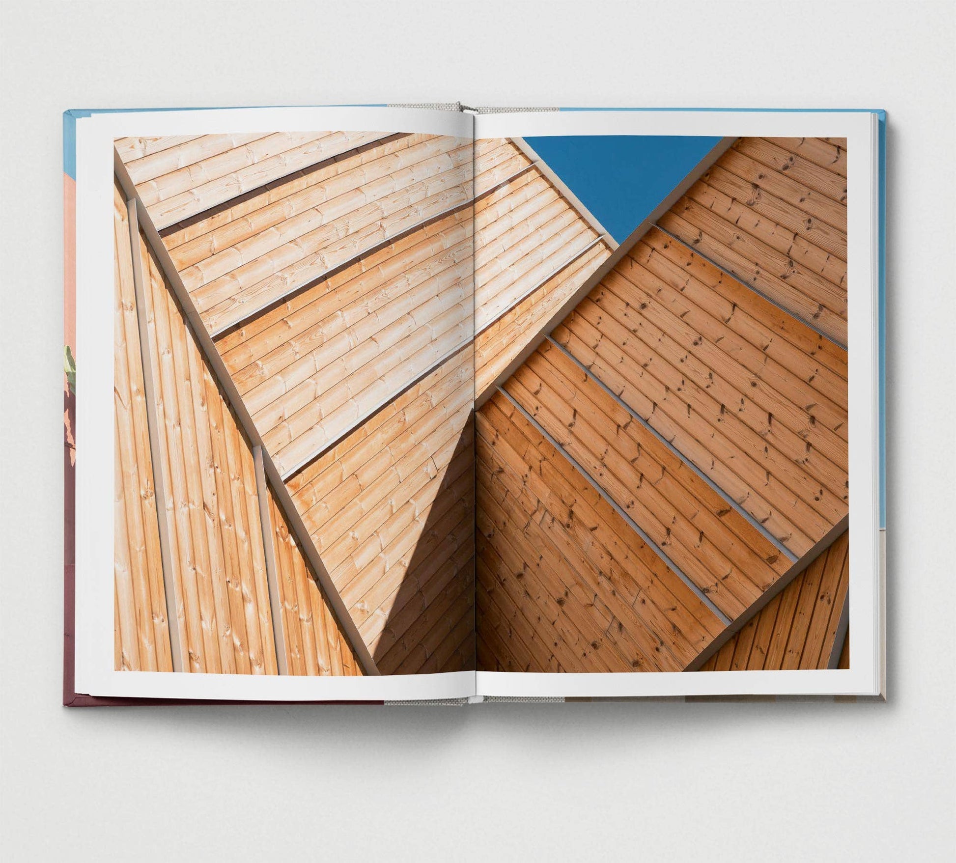 Open book showing a detailed view of wooden architecture with a blue sky background.