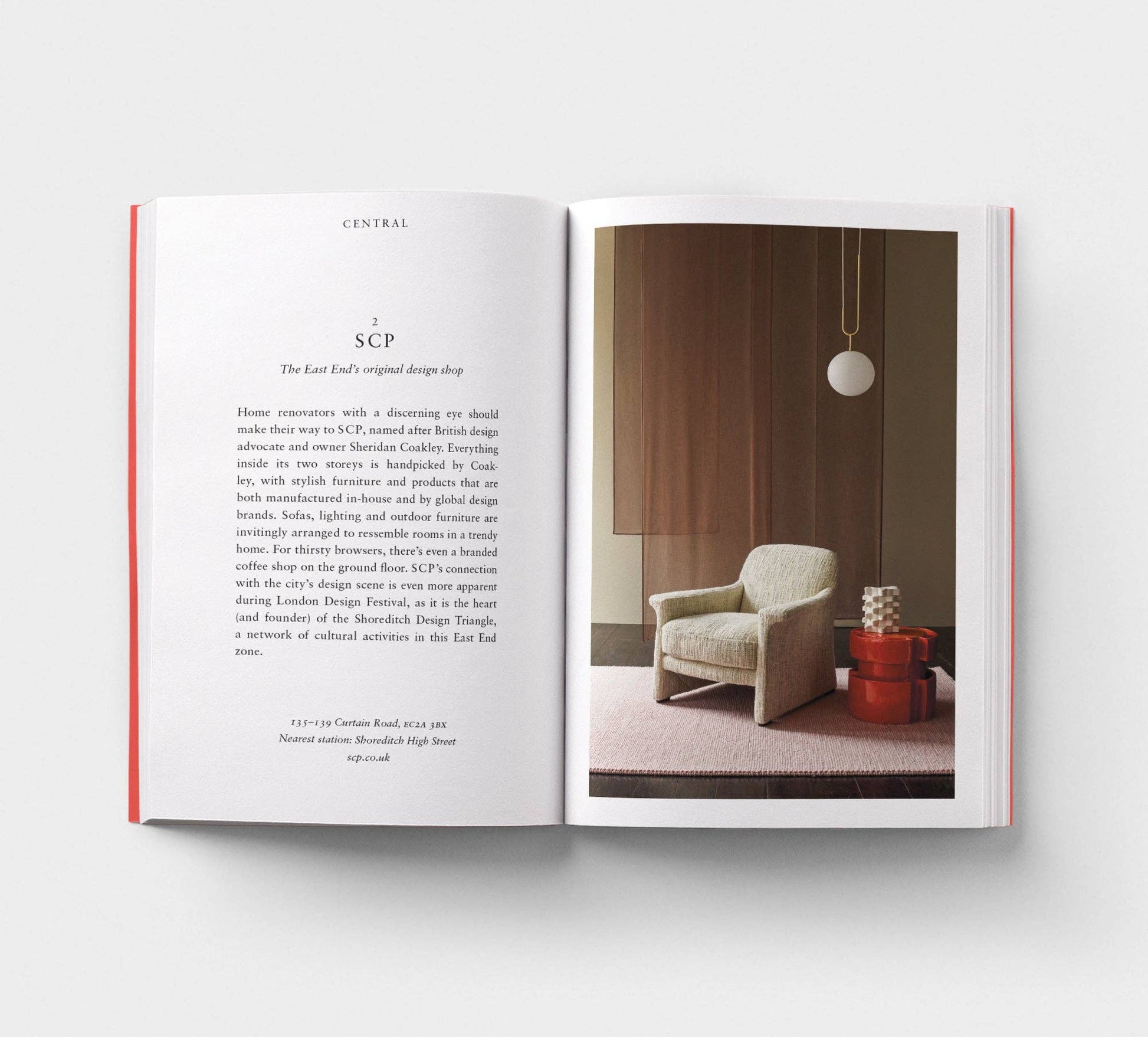 Open book showing interior design layout with text and a photo of a room with a chair and lamp.