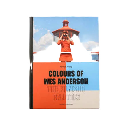 Book titled 'Colours of Wes Anderson' with a person in an orange dress on a lighthouse background.